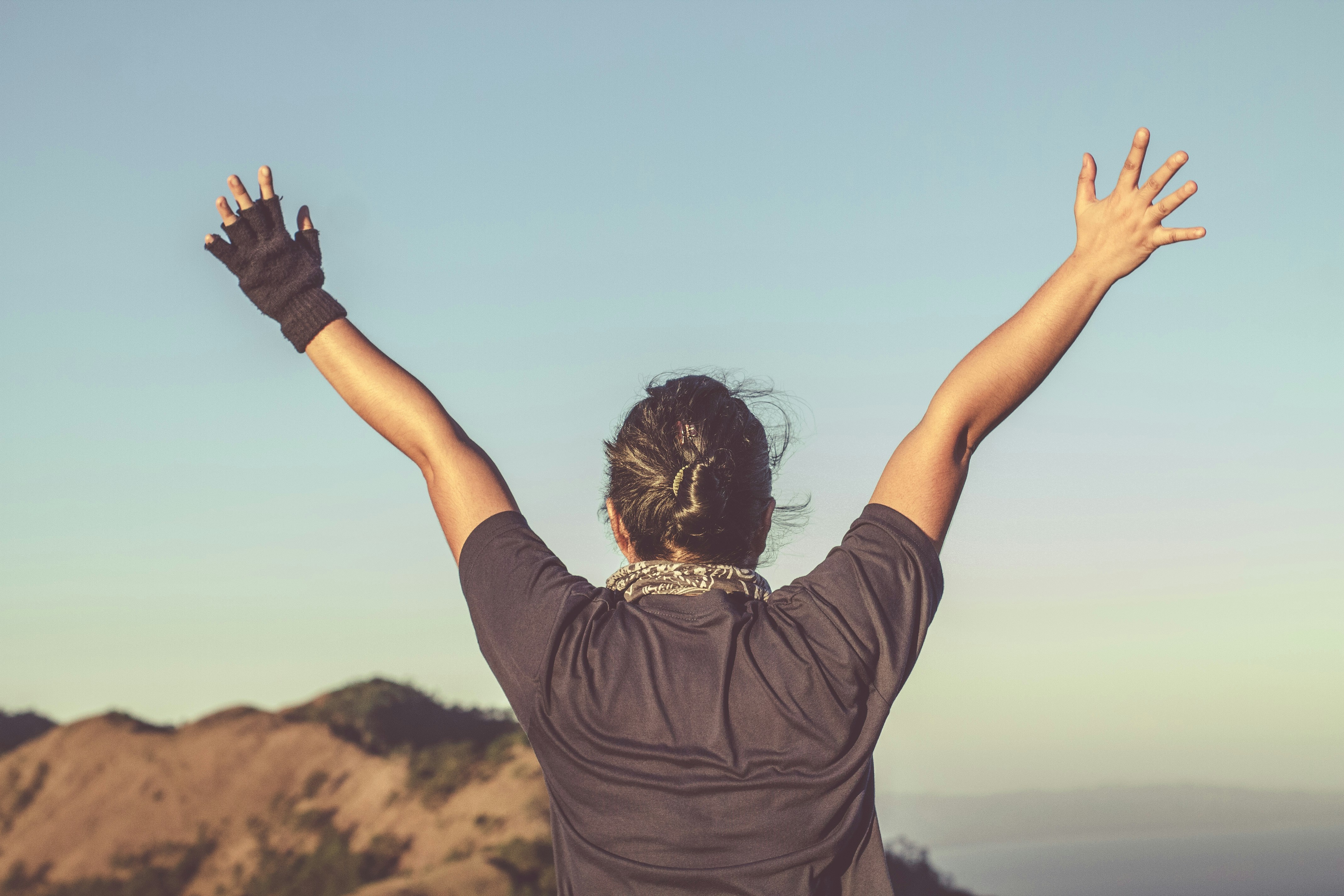 Person with arms raised wide against an open sky - the feeling of going further